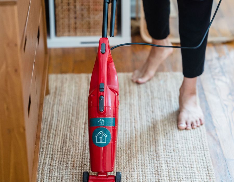 A cleaner vacuuming a fitted carpet during a deep clean in a home