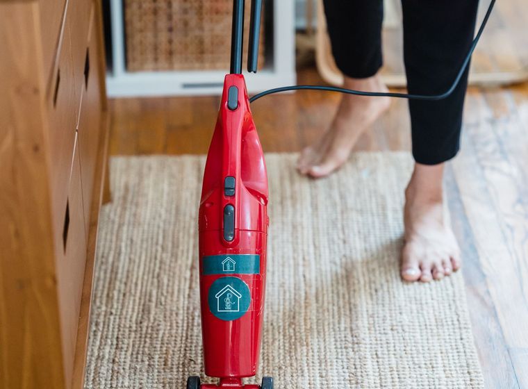 A cleaner vacuuming a fitted carpet during a deep clean in a home