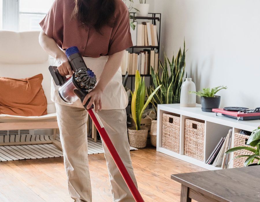 A cleaner vacuuming the carpet of a bright, tidy living room in a Bahrain home